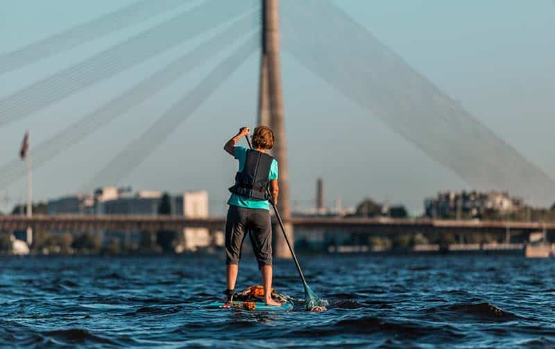 paddle boarder moving toward bridge