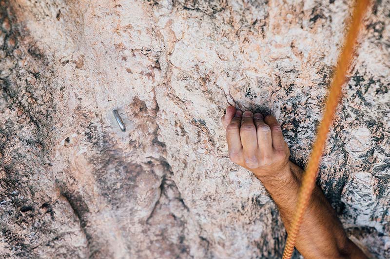 arm of climber on rock with climbing rope