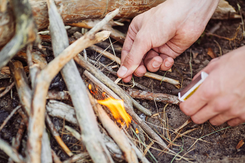 man kindles a fire in summer wood