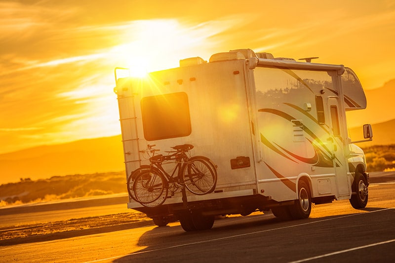 rv on road at sunset